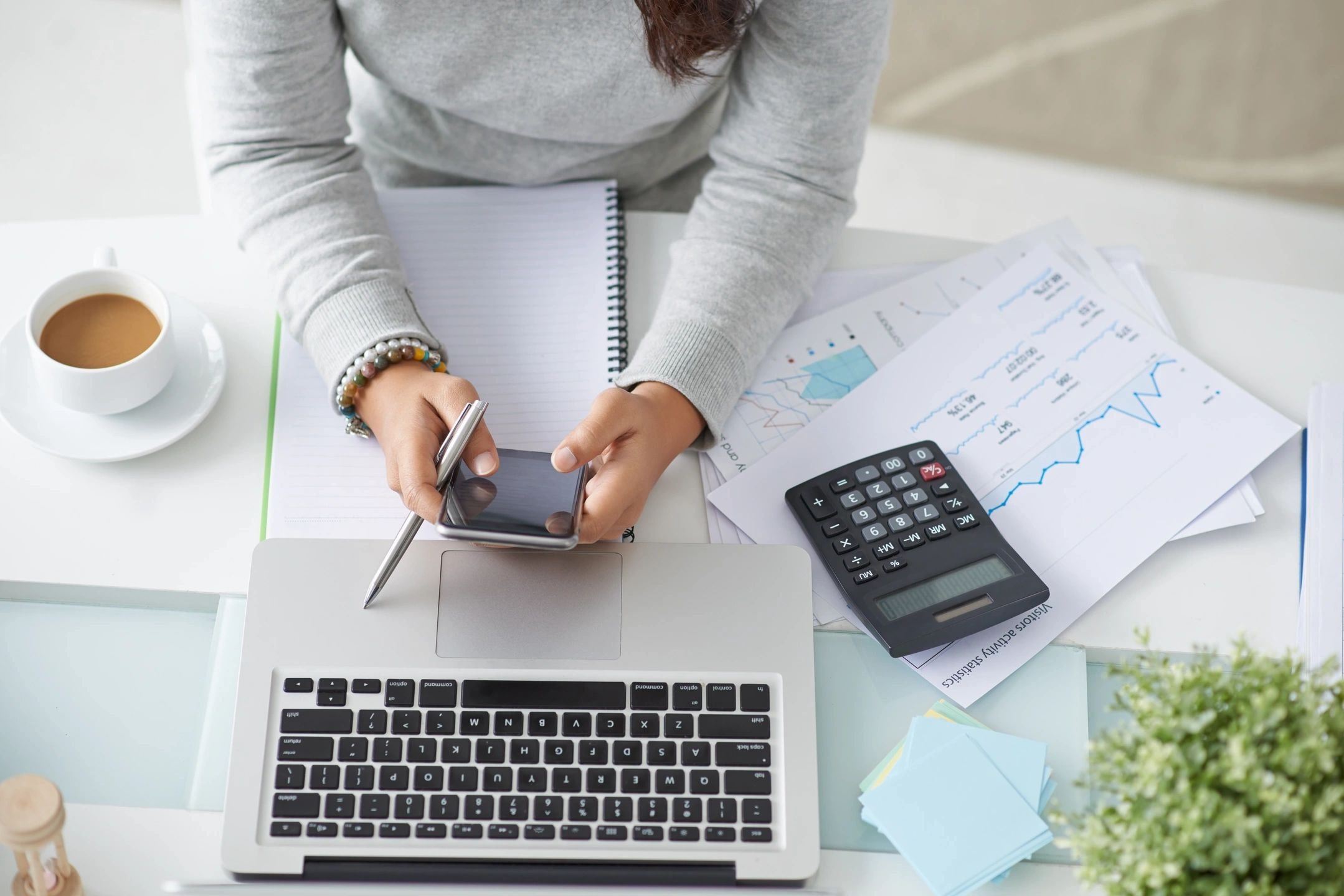 Person working at desk with calculator and financial charts